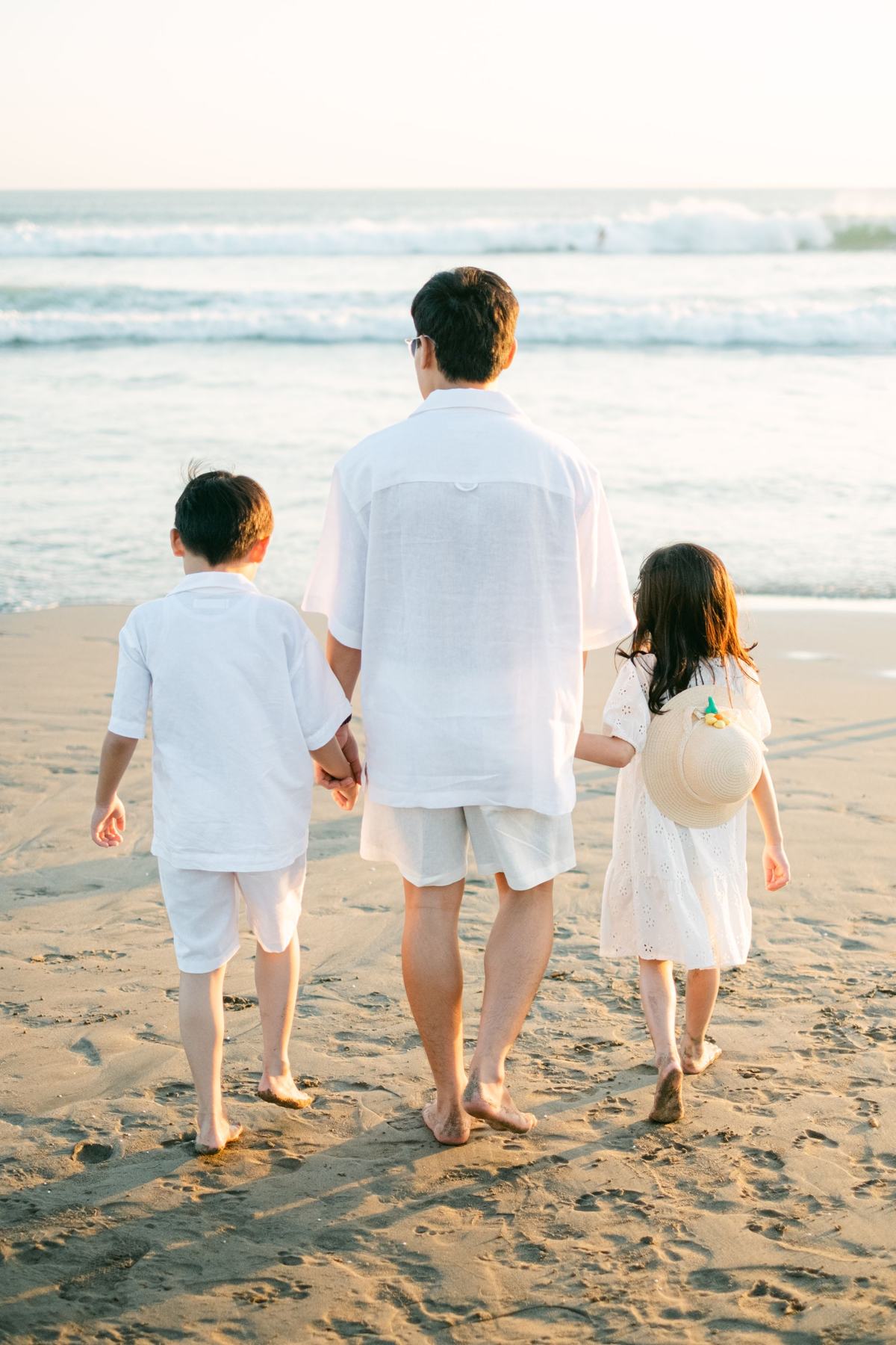 A family walking toward the ocean, seen from behind
