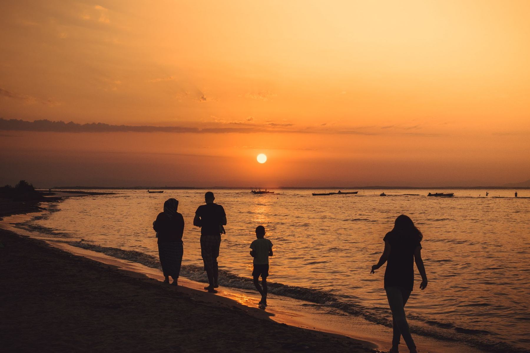 A family walking along the shoreline at sunset