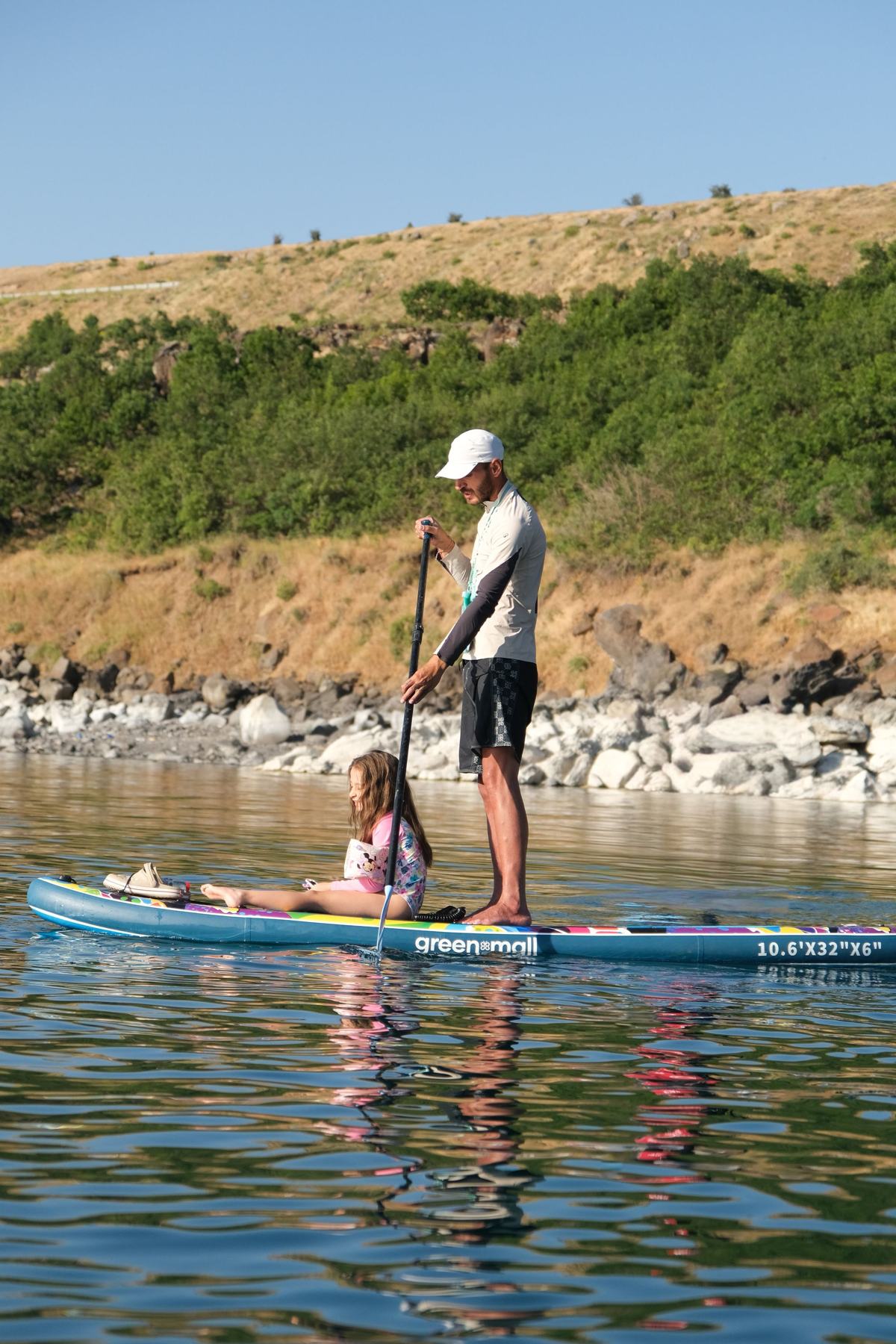 A parent and child paddleboarding on a calm lake